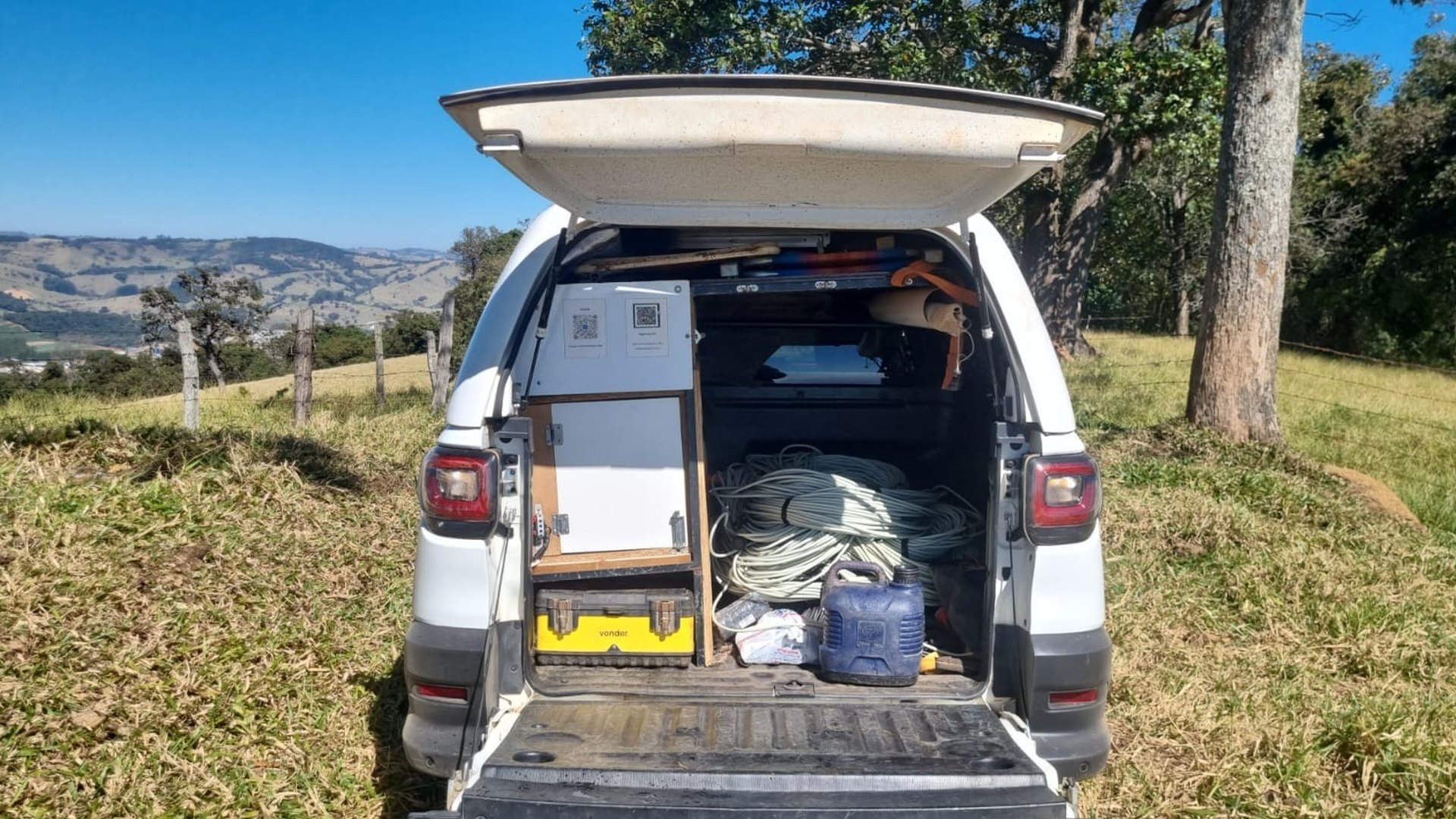 Porta-malas de um carro de campo da Aqua Liber com bobinas de cabo e equipamento de eletrorresistividade real — o "detector" de verdade vem com cabos, eletrodos, dados e laudo