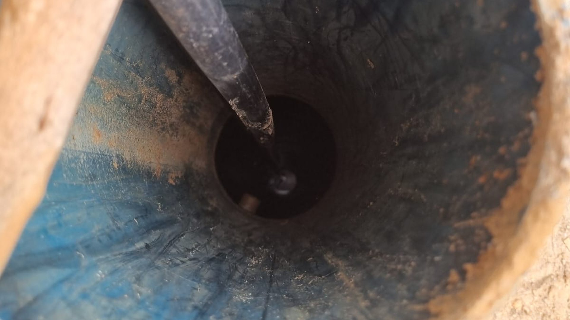Boca de um poço tubular vista de cima, com a tubulação descendo pelo revestimento — olhando de cima não dá para saber a profundidade do poço