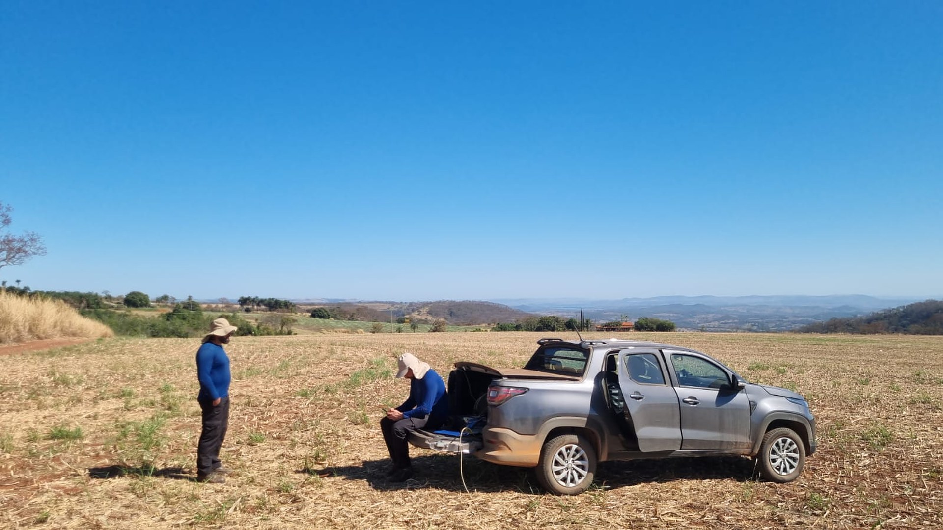 Técnicos da Aqua Liber com a picape em área de estudo geofísico num talhão colhido — a leitura do subsolo antes da sonda diz se 50 metros bastam