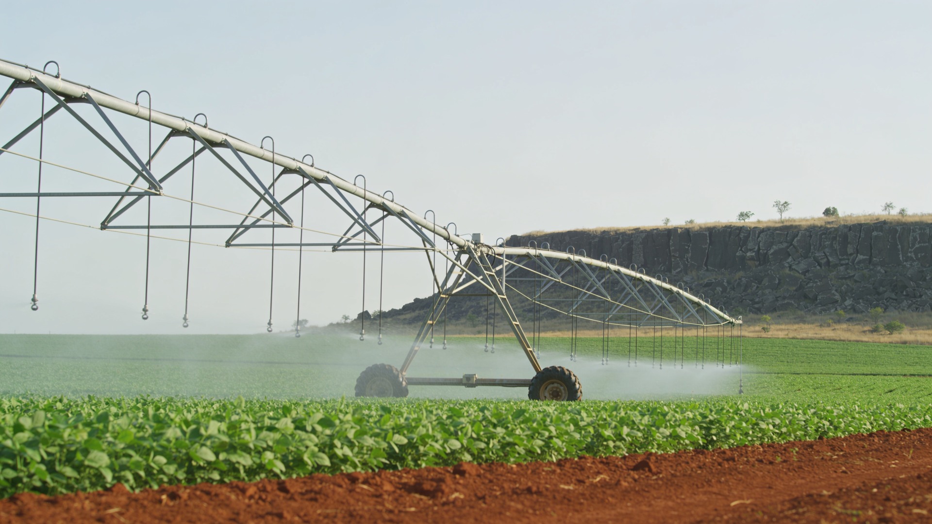 Contraste entre terreno sedimentar com pivô central e afloramento de basalto fraturado ao fundo